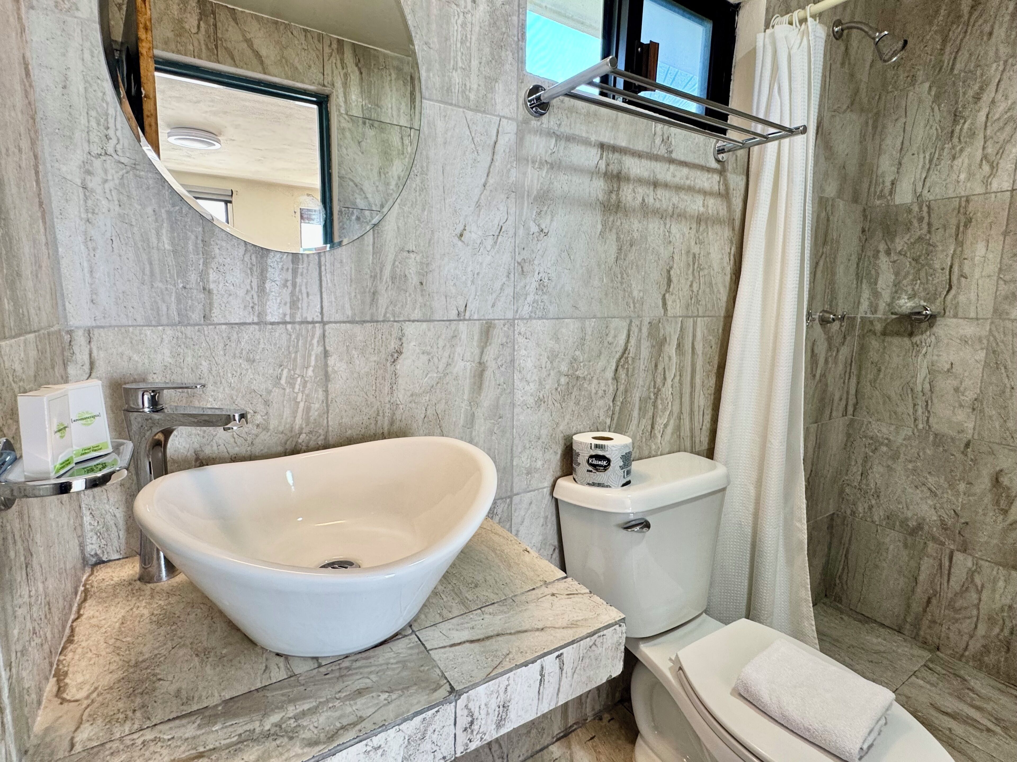 A bathroom with a freestanding sink, toilet, and shower.