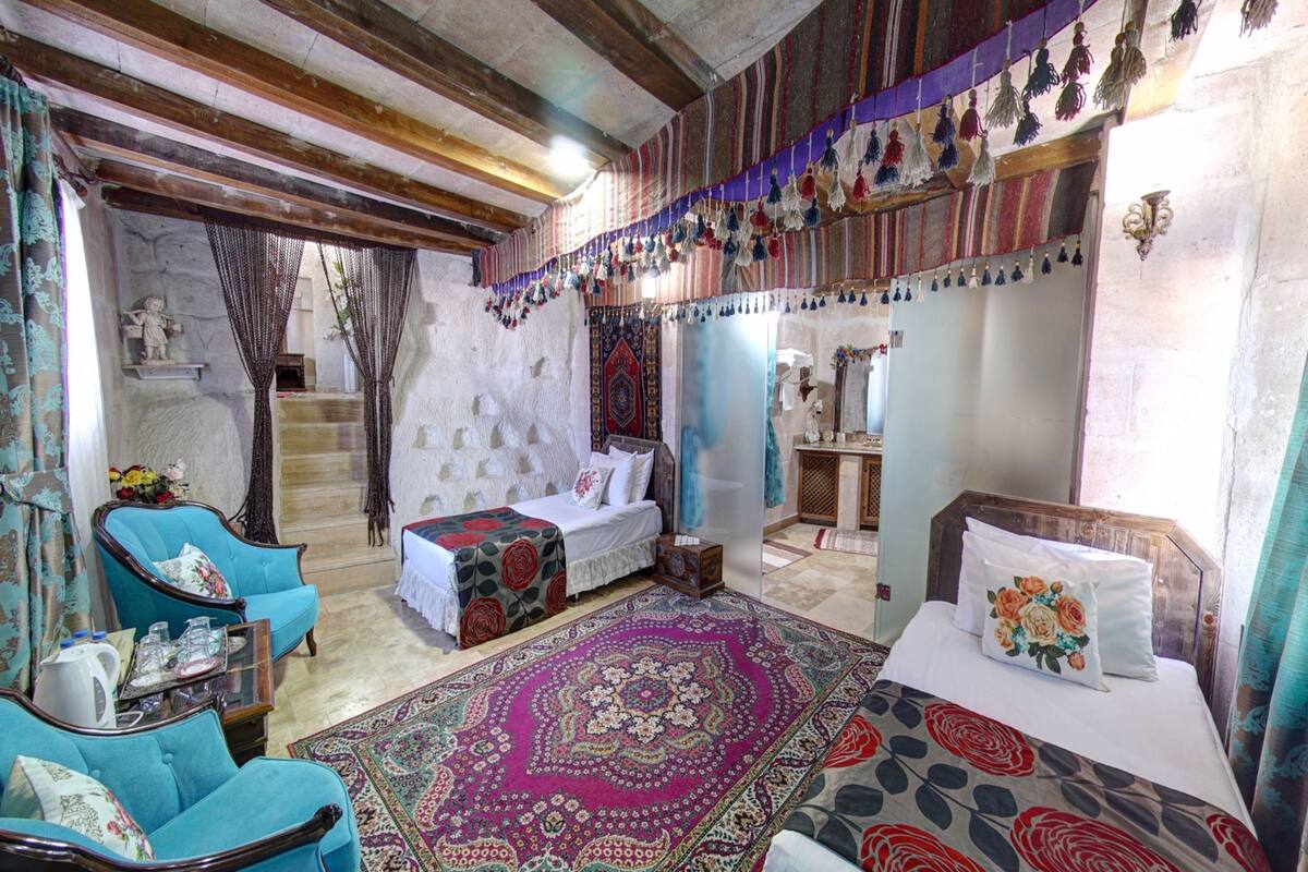 A traditional room with a bed, a sofa, and a small table. There is a staircase leading to another level.