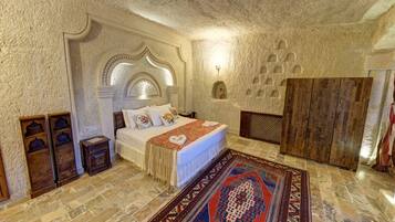 Un dormitorio con una cama grande, un tapete estampado y una pared de piedra.