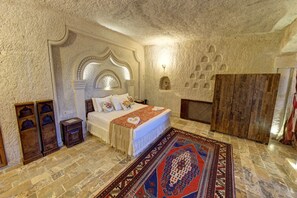Une chambre avec un grand lit, un tapis à motifs et un mur en pierre.