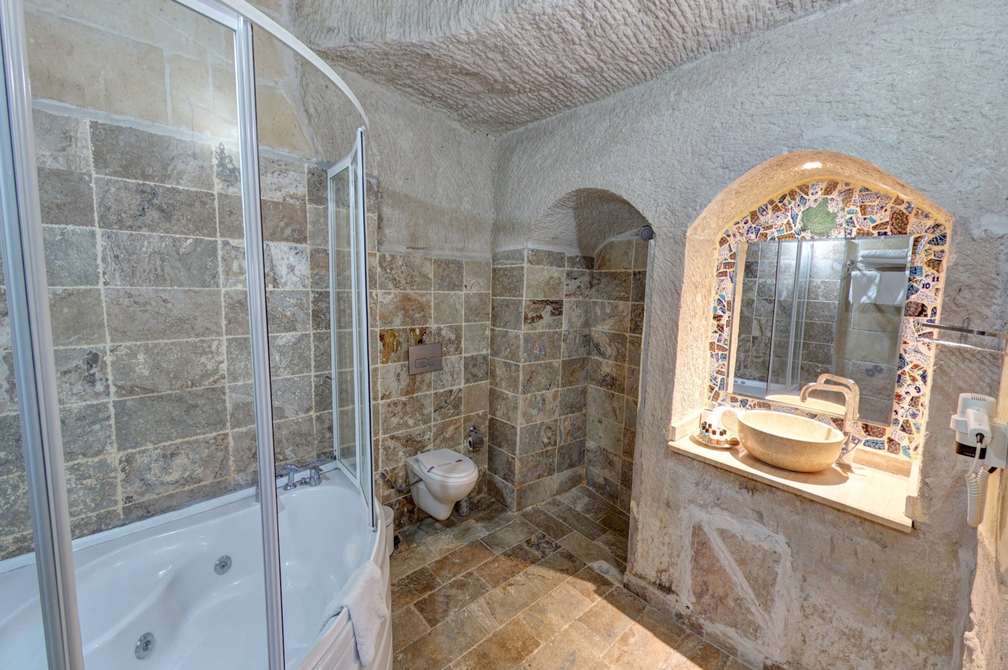 Une salle de bain avec une baignoire, une douche et un lavabo agrémenté d’un miroir en mosaïque.