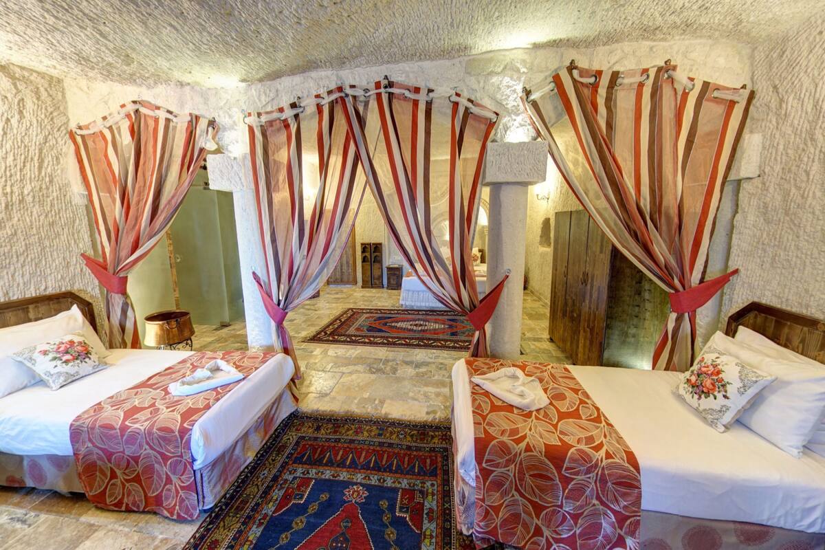 A hotel room with two beds, a large rug, and a view of a courtyard.