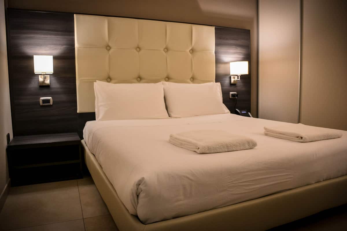 A neatly made bed with a tufted headboard, two bedside lamps, and a small bedside table.
