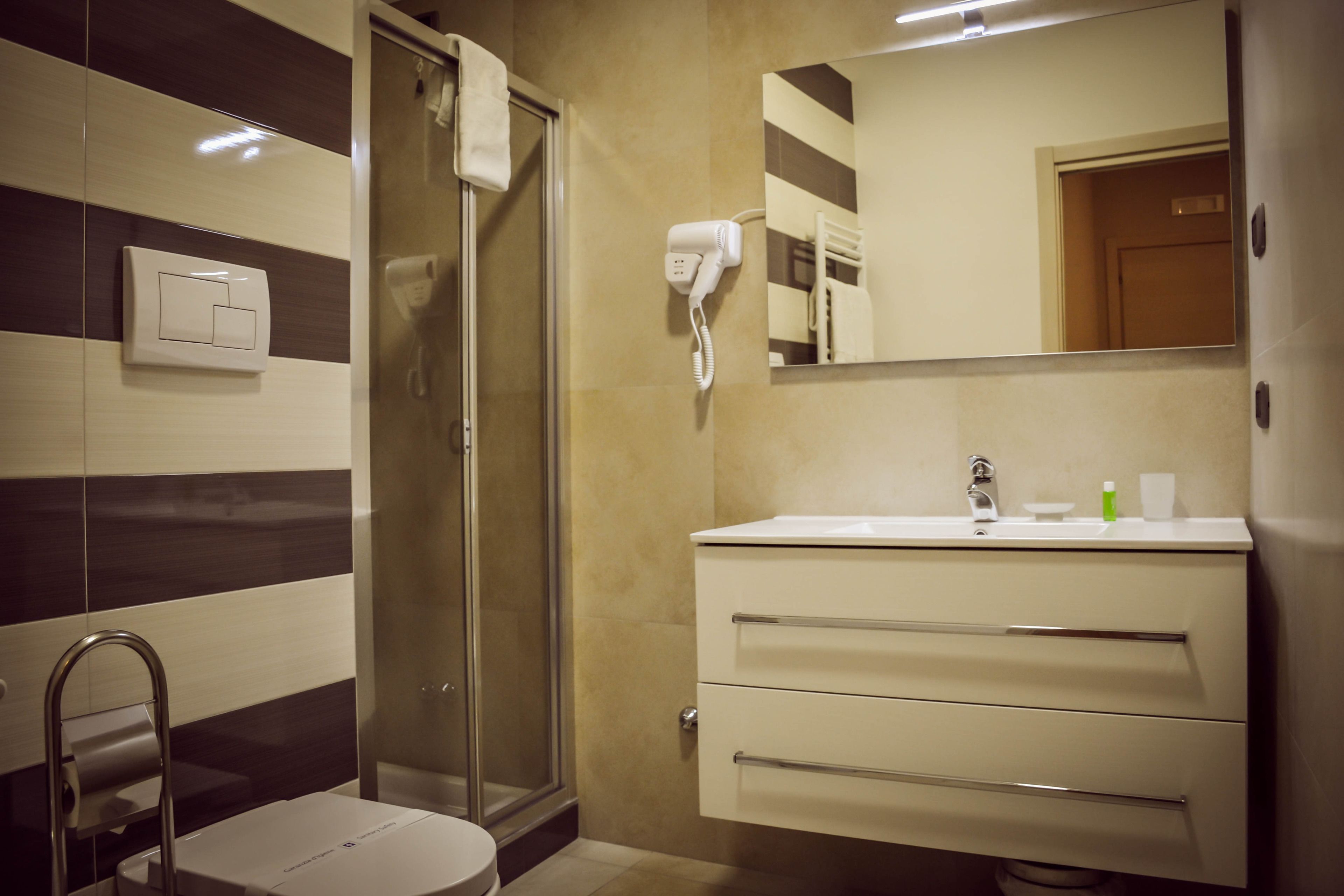 Un baño moderno con ducha, inodoro, tocador y espejo.