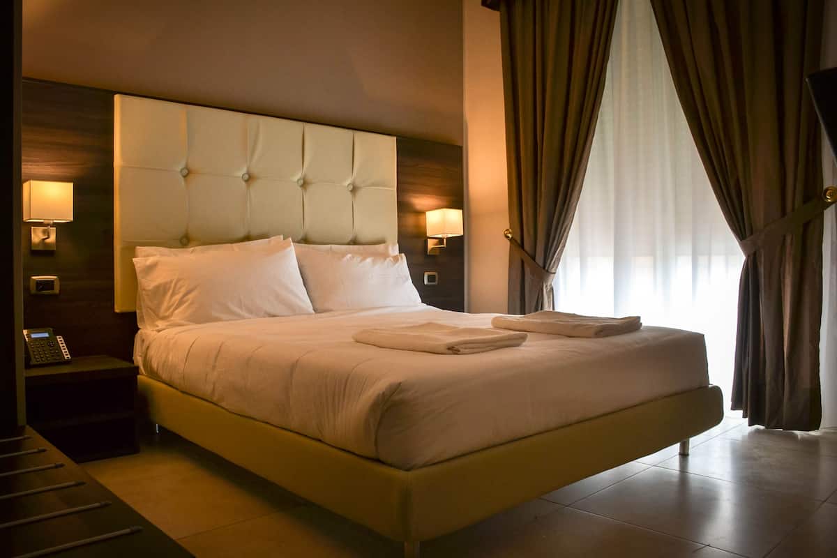 A hotel room with a large bed, a bedside table with a lamp, and a telephone.