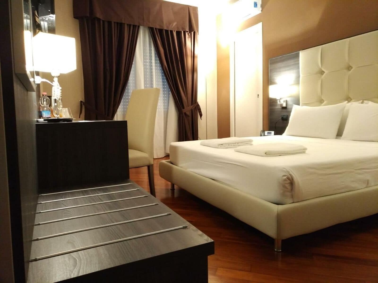 A hotel room with a bed, a desk, and a chair.