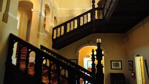 A grand staircase with ornate balustrades, leading to a landing with a door marked "EXIT" and a fire extinguisher on the wall. - Kearsney Manor Guesthouse (KwaDukuza)