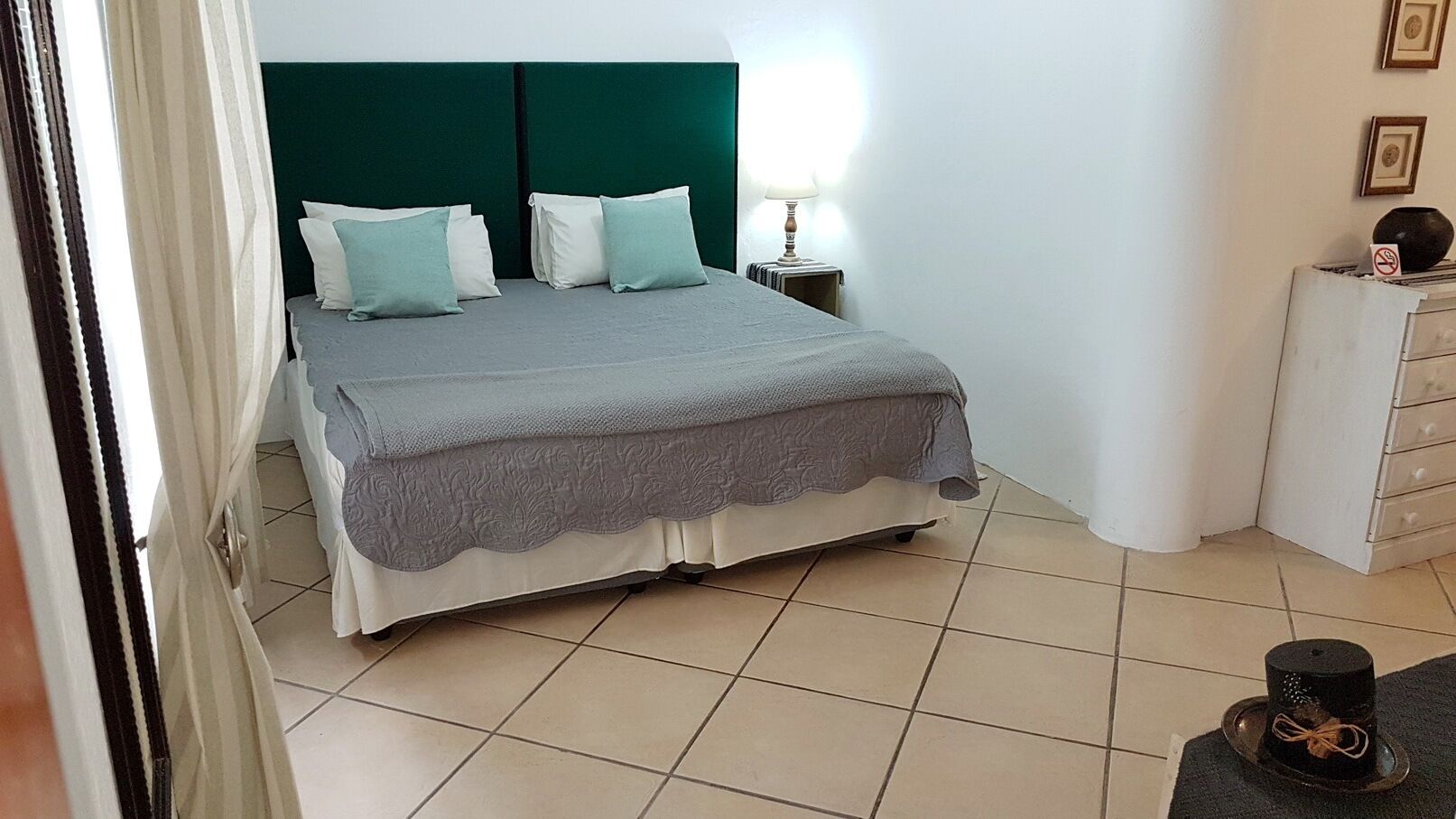 Un dormitorio con cama, mesita de noche, lámpara y cómoda.