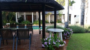A covered outdoor area with a pool, seating, and potted plants. - Six Valk Avenue Guest House (Sandton)