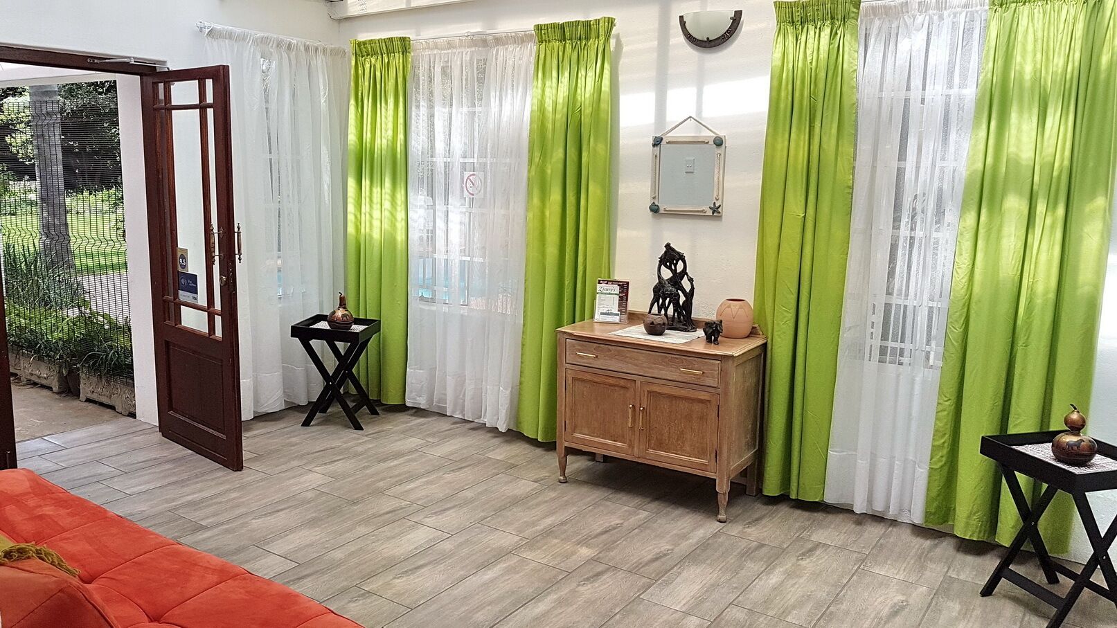 Una habitación con un armario de madera, una pequeña mesa con un florero y un sofá rojo.