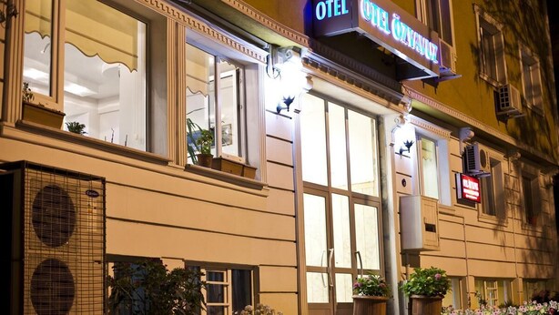 Un hôtel avec une grande enseigne sur laquelle on peut lire « OTEL ÖZYANUZ » et de grandes fenêtres.