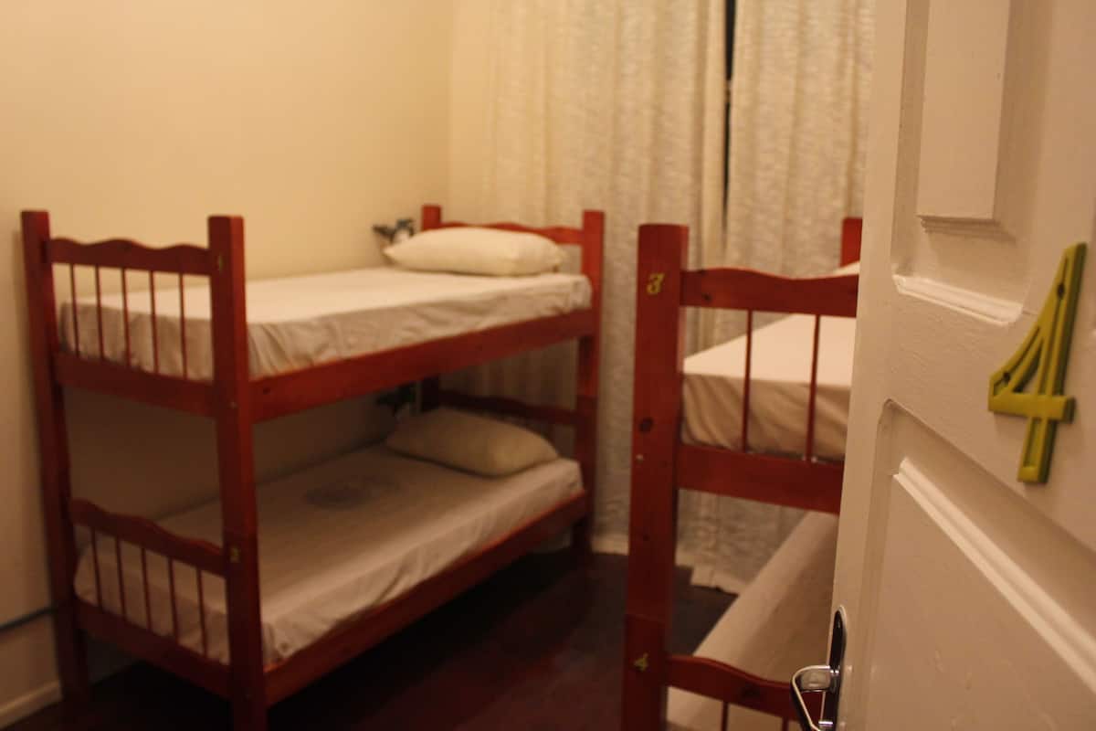 A room with two bunk beds, a white door with a number, and a curtain.