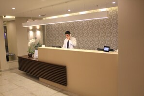 A reception desk with a modern design, a digital screen, and a potted plant. - Hostel by Hotel Galicia (Rio de Janeiro)