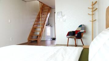 Quarto com escada de madeira, uma cadeira colorida e uma cama.