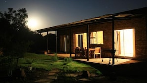 A house with a covered patio, a dining area, and a large window. - Thirsty Falls Guest Farm (Maanhaarand)