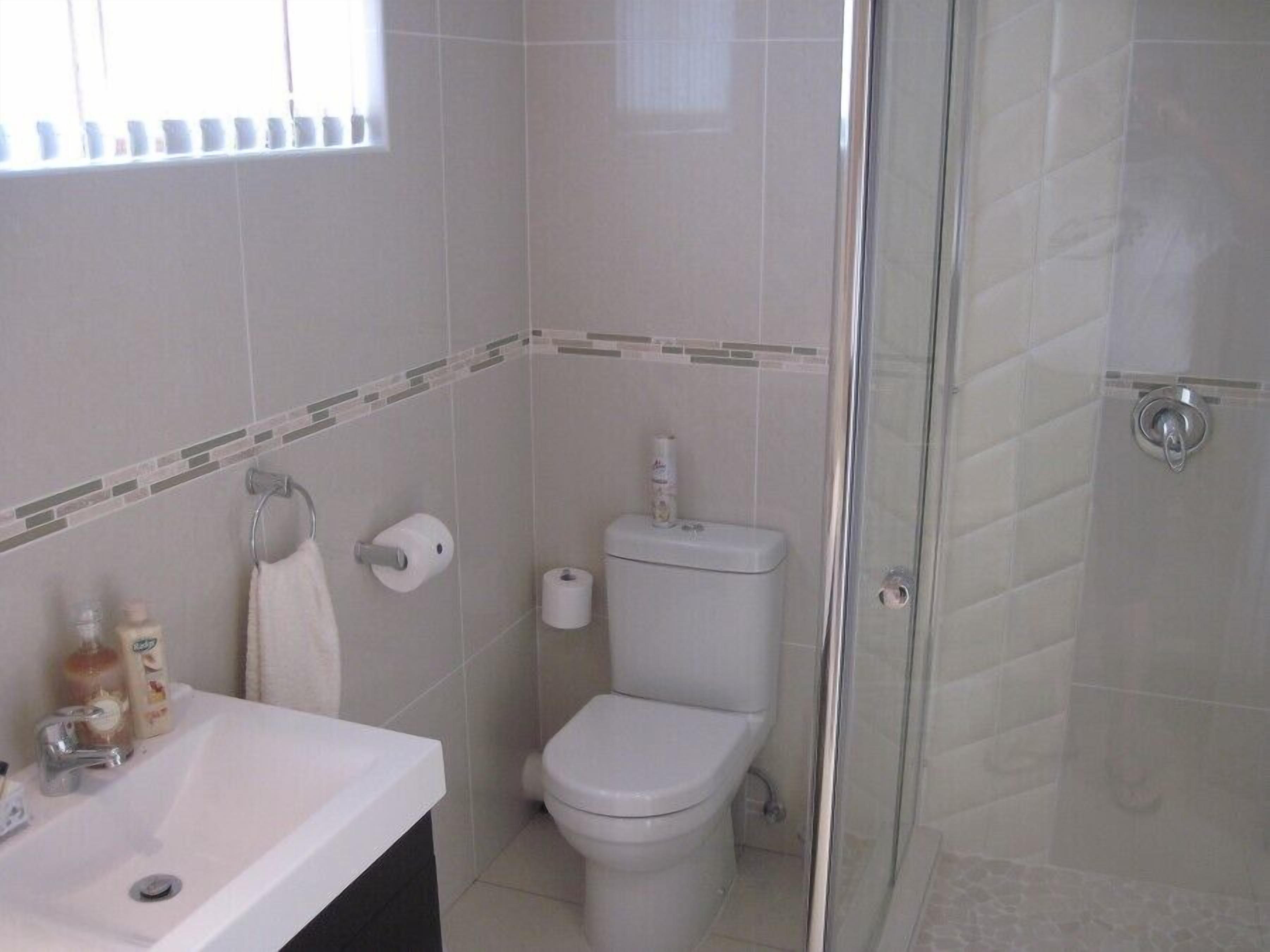 A bathroom with a white sink, toilet, and glass shower enclosure.