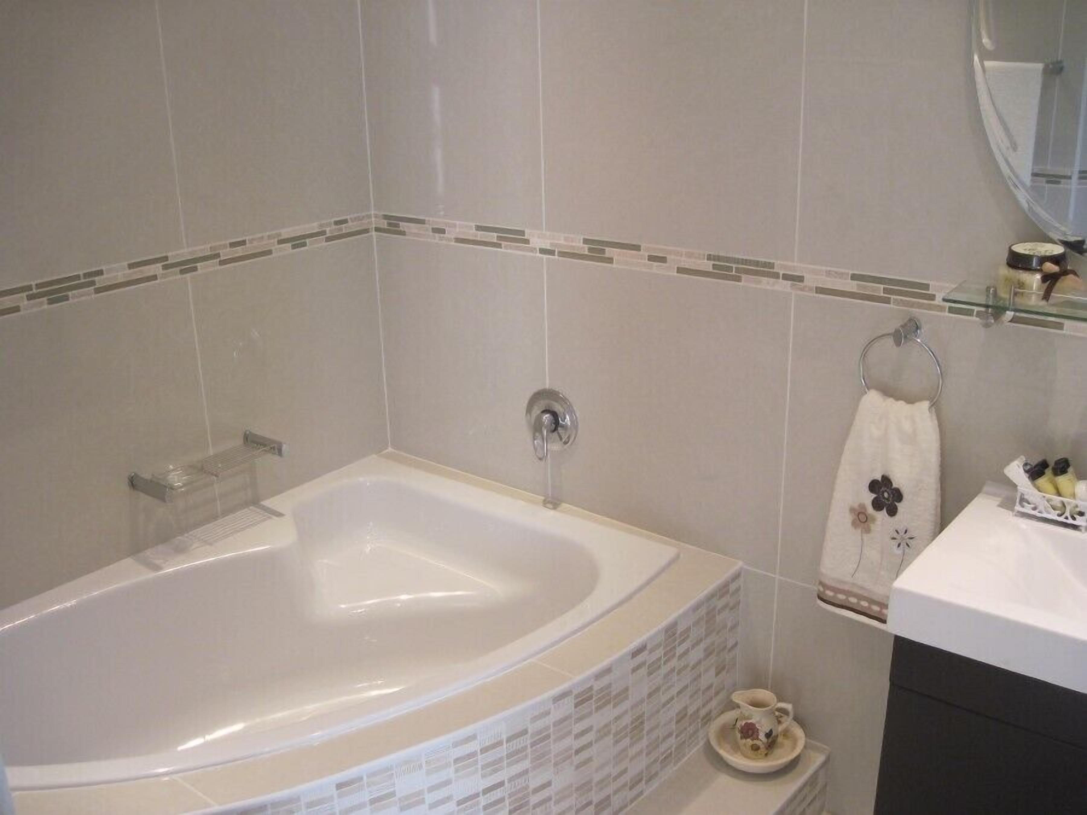 A bathroom with a large bathtub, a sink, and a mirror.