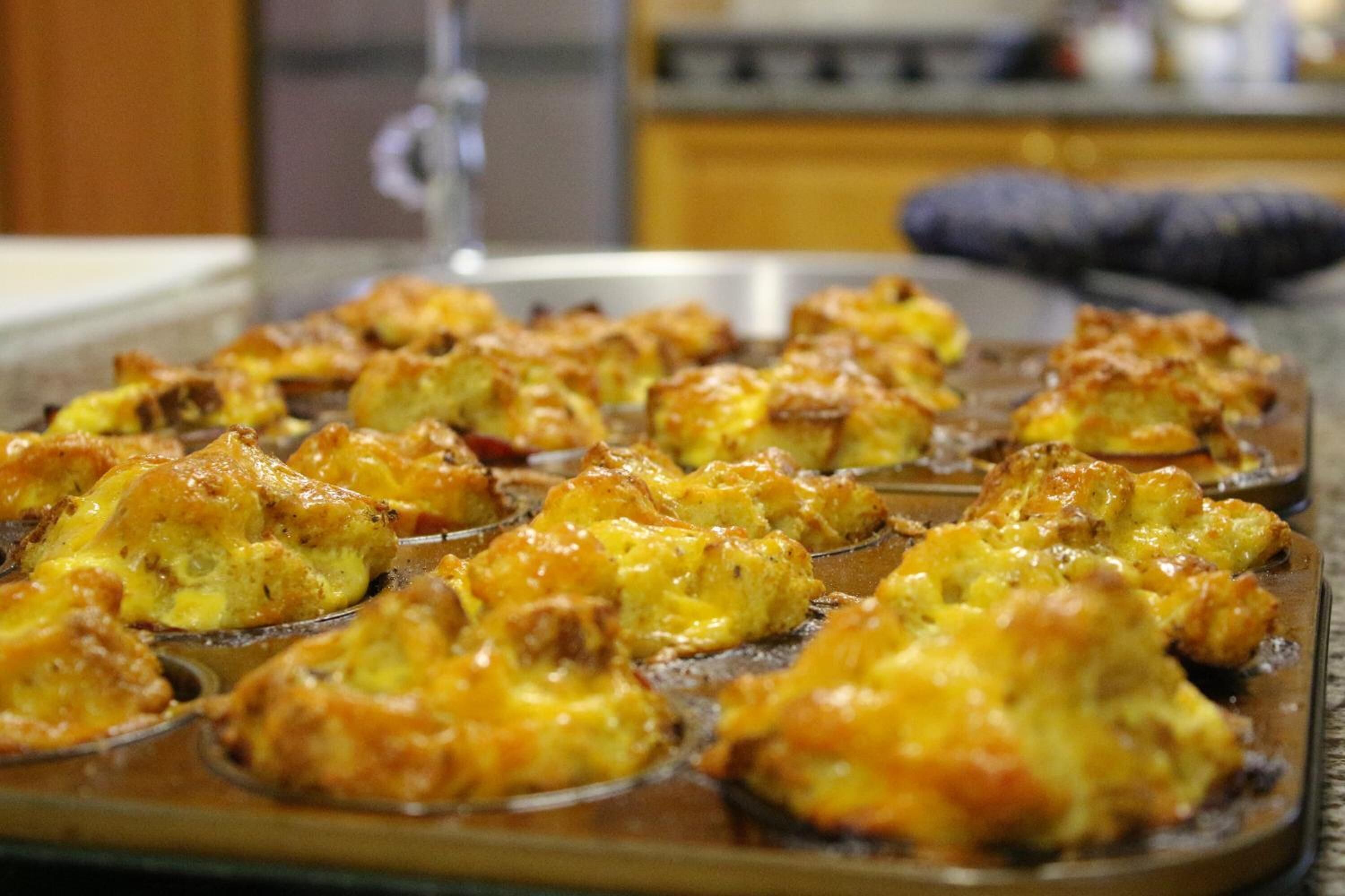 A tray of baked goods with a golden-brown crust, possibly muffins or biscuits, arranged on a baking tray.