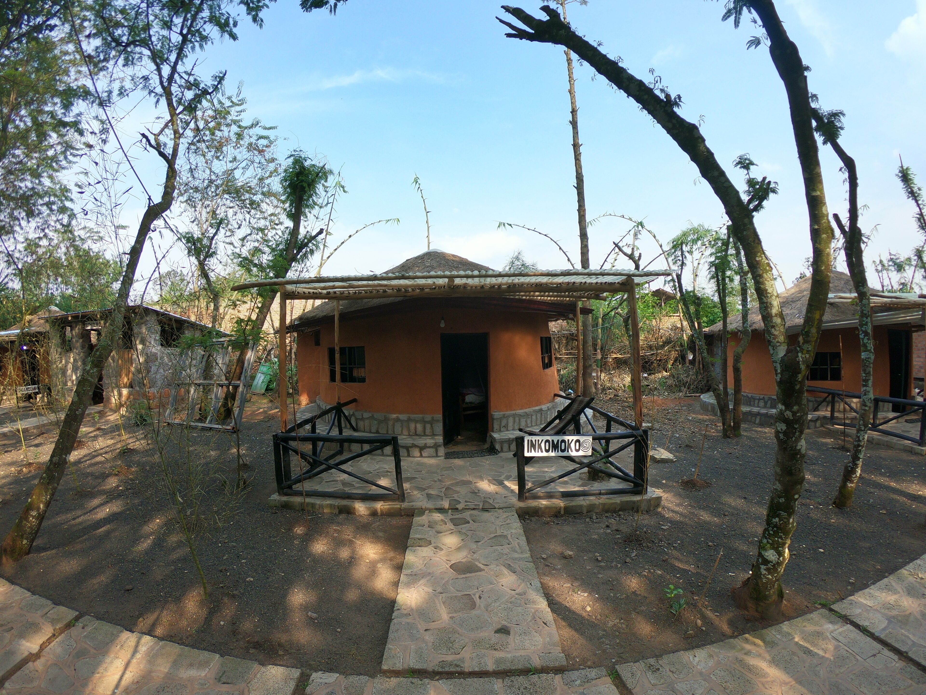 A rustic building with a thatched roof, surrounded by trees and a stone pathway.