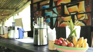 Een tafel met een thermoskan, een fruitschaal en een koffiezetapparaat.