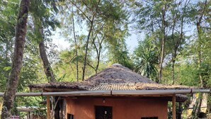 A rustic building with a thatched roof, a wooden door, and a small porch. - Red Rocks Rwanda Guesthouse & Campsite (Nkotsi)
