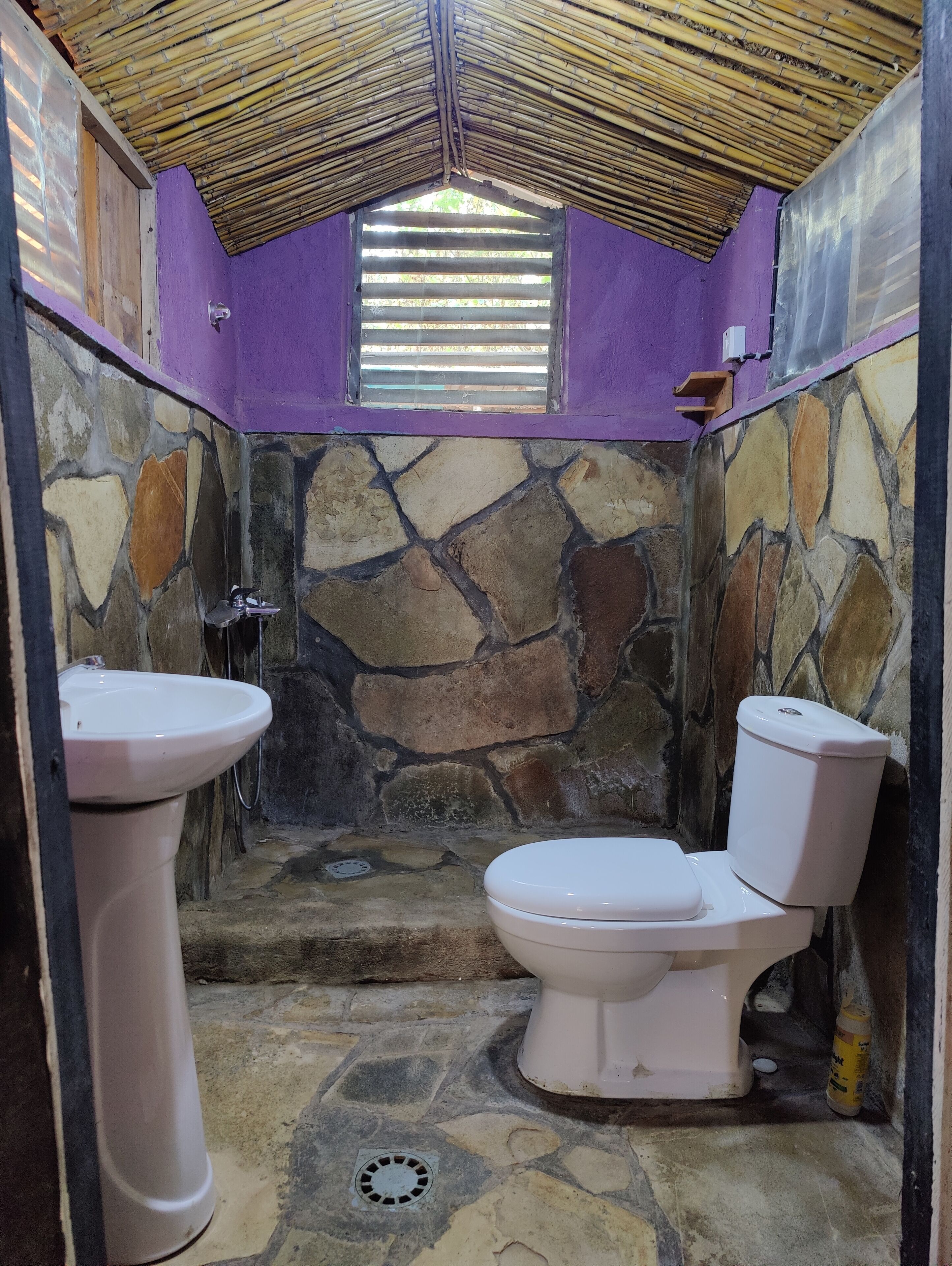 A bathroom with a stone wall, a toilet, and a sink.