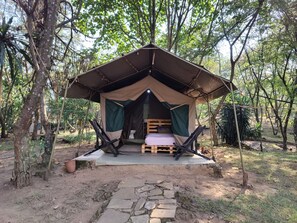 A tent with a bed, a bench, and a toilet.