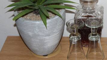 A potted plant with long green leaves, a textured white pot, and two clear glass bottles with a stopper on a wooden surface.