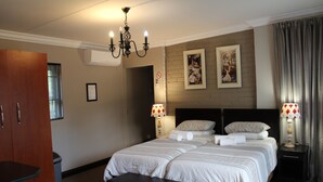 Habitación de hotel con una cama grande, un armario de madera, un banco y una araña.