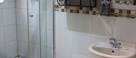 A bathroom with a glass-enclosed shower, a pedestal sink, and a toilet.