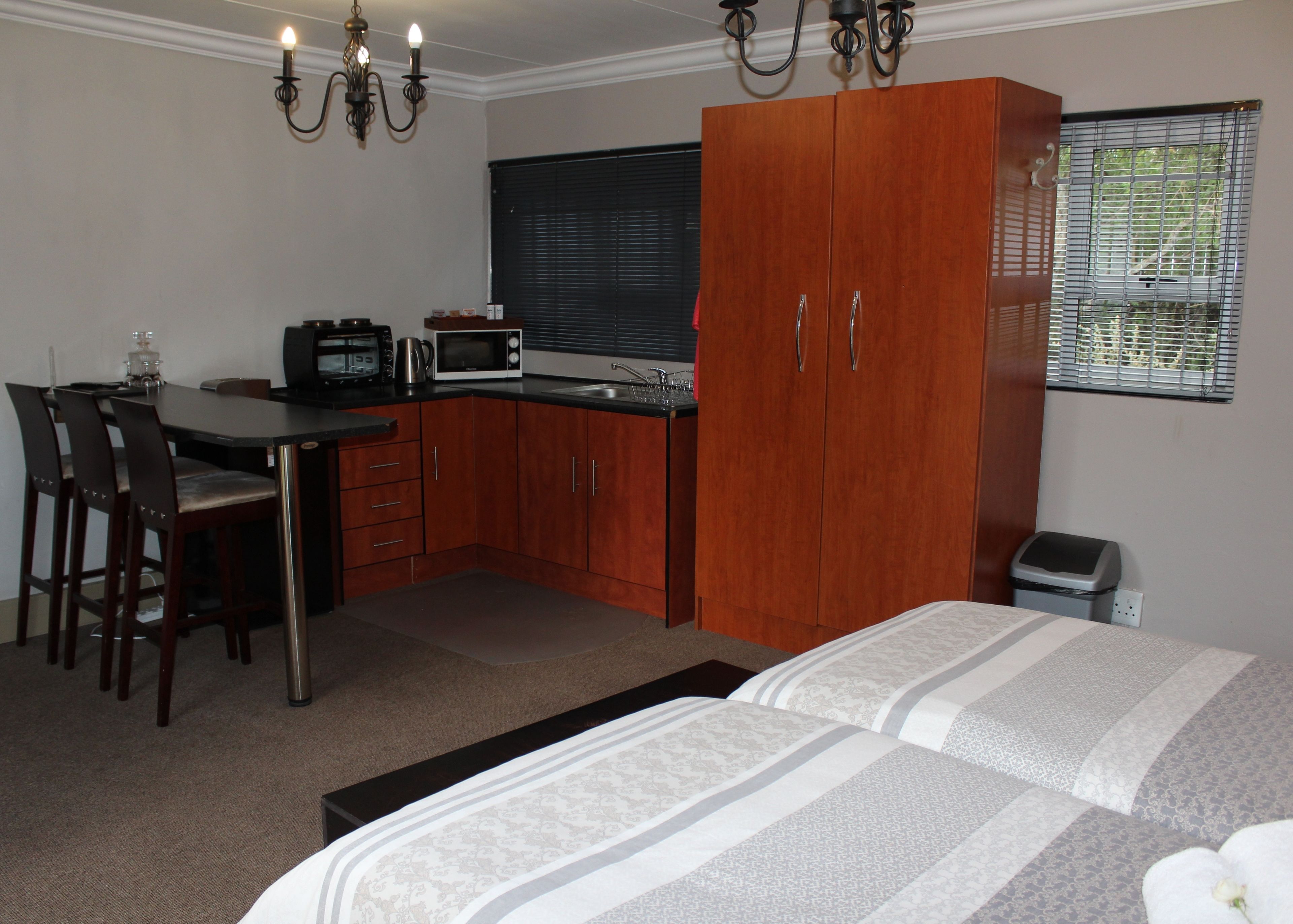 A compact bedroom with a bed, a small kitchenette, and a dining area.