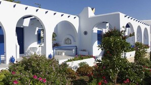 A white building with blue accents, featuring arches and a courtyard with seating. - Bungalows Marina (Paros)
