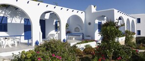 A white building with blue accents, featuring arches and a courtyard with seating. - Bungalows Marina (Paros)