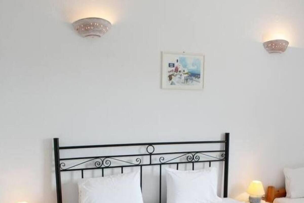 A neatly made bed with a patterned bedspread, two bedside lamps, and a framed picture on the wall.
