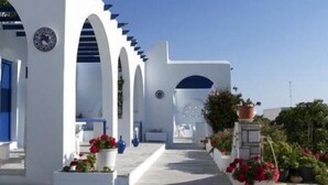 A white building with blue accents and a tiled pathway leading to a door. - Bungalows Marina (Paros)