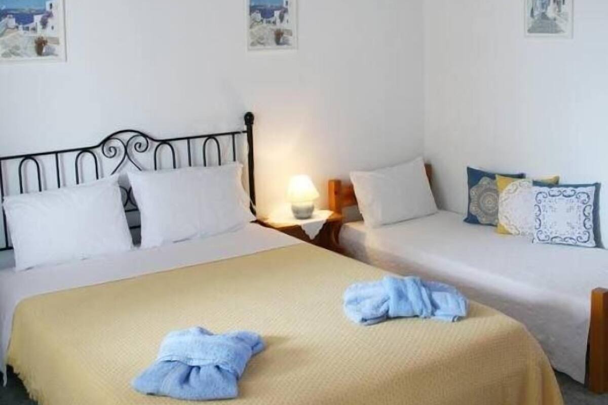 A bedroom with two beds, a ceiling fan, and artwork on the walls.