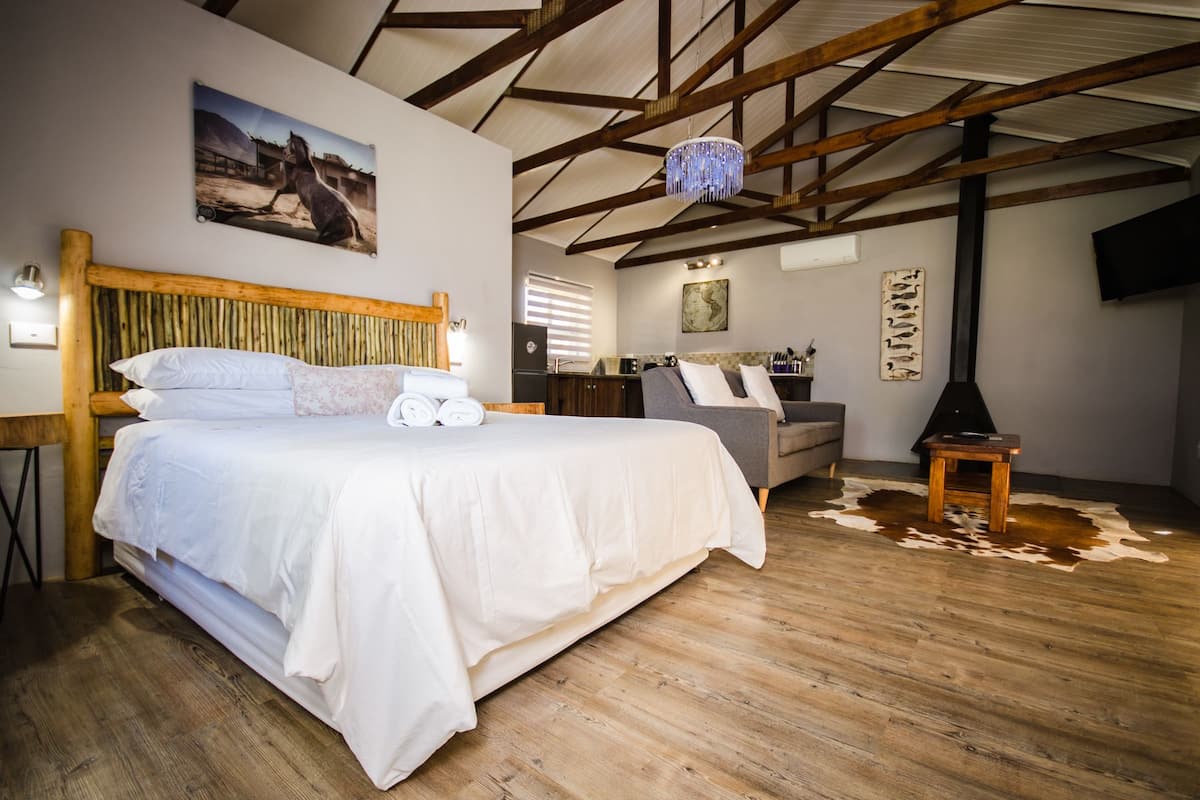 A bedroom with a large bed, a wooden headboard, a desk, a sofa, and a television.