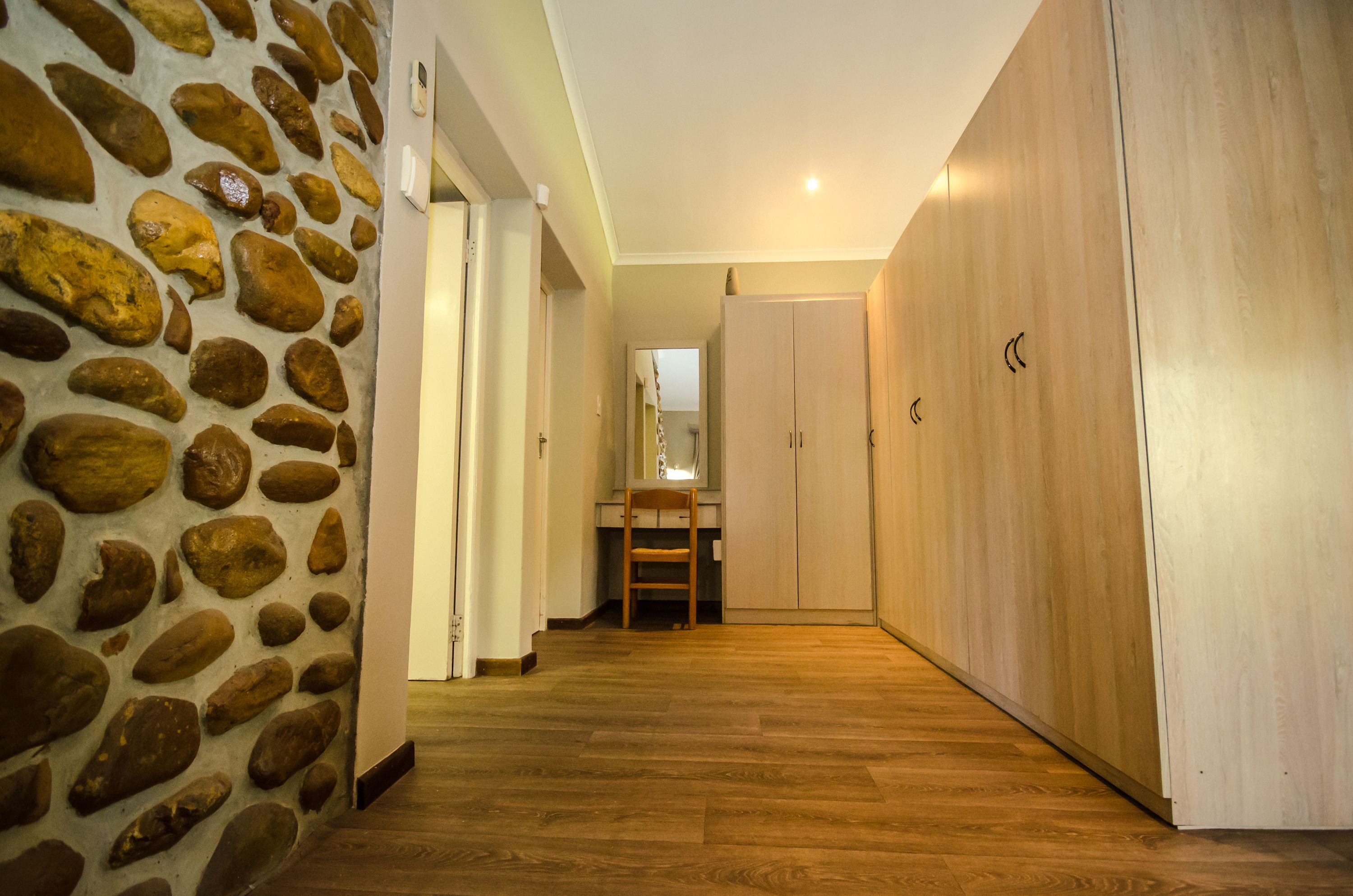 A hallway with a stone wall, wooden flooring, and a wooden wardrobe.