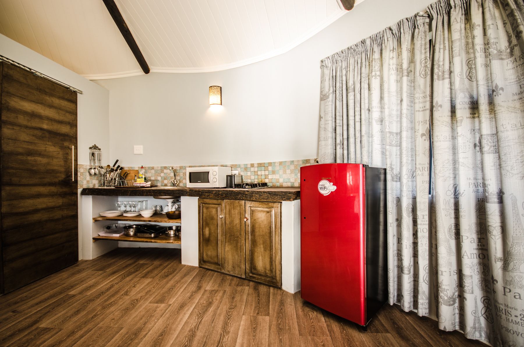 A compact kitchen with wooden cabinets, a red refrigerator, a microwave, and a small sink area.