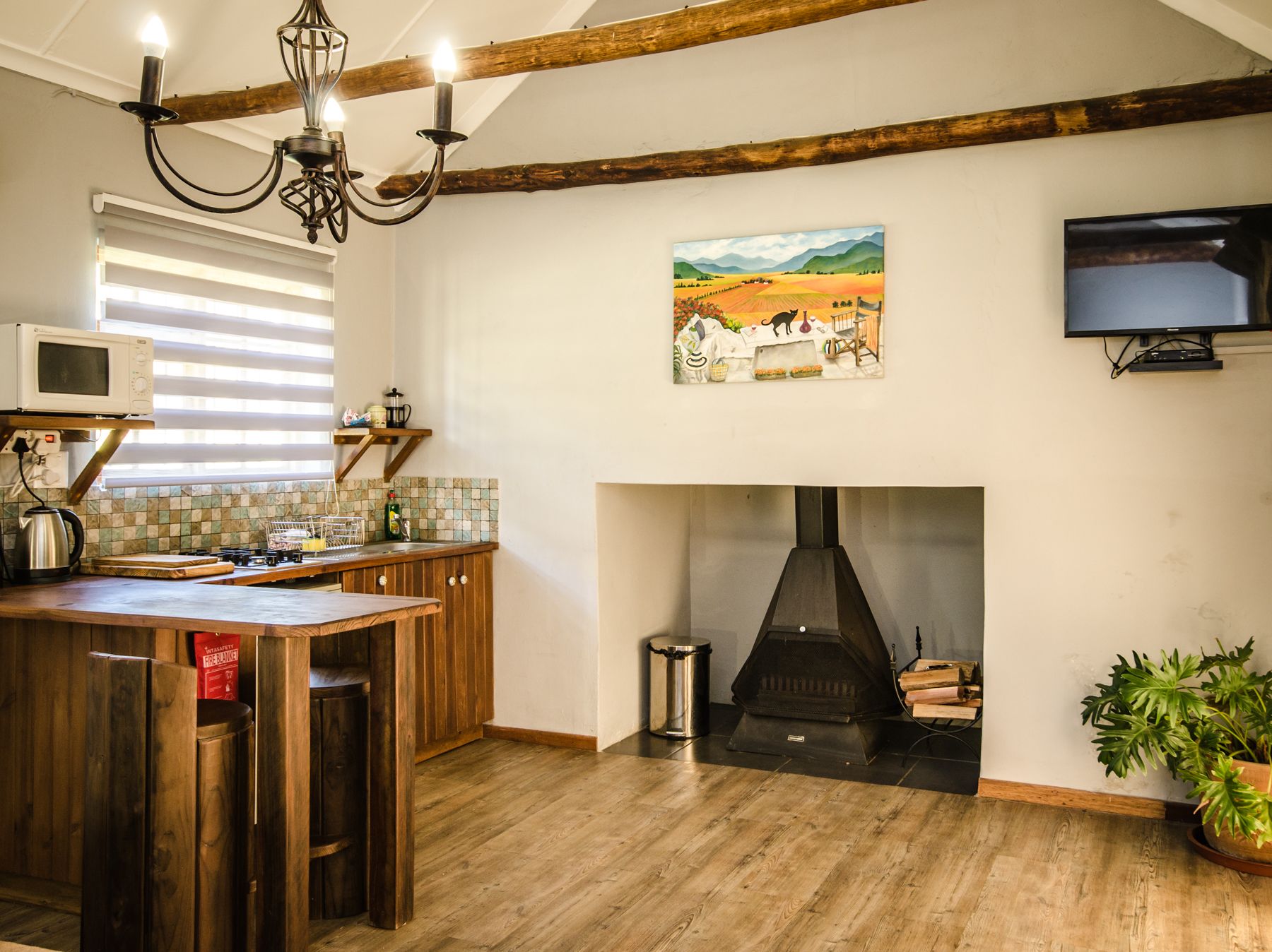 A kitchen with a wooden island, a fireplace, a television, and a painting on the wall.