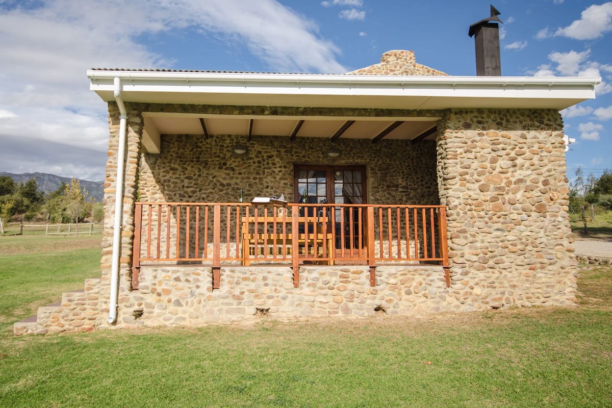 A stone building with a wooden balcony, a chimney, and a door.