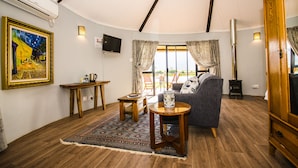 A cozy living room with a sofa, a TV, a fireplace, and a painting on the wall. - Reflections Guest Farm (Tulbagh)