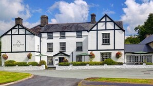 A traditional white building with black trim, named 'Brigands Inn', featuring a symmetrical facade, multiple windows, and a central entrance.
