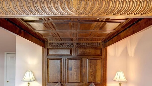 A bedroom with a large bed, two bedside tables, and a wooden ceiling with intricate carvings.