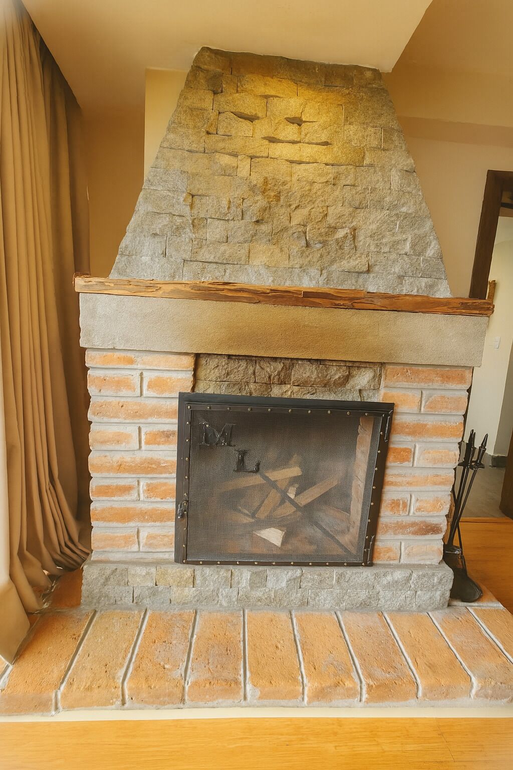 A stone fireplace with a wooden mantel and a metal screen door.