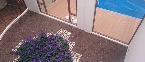 Eine Treppe mit einem Blumenbeet am Fuß, einem Holzboden und einer Glastür zu einem Außenbereich.