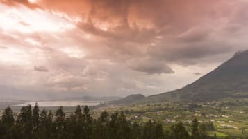 Vista panorámica de un paisaje montañoso con un pueblo en el valle, un lago y un puente a lo lejos.