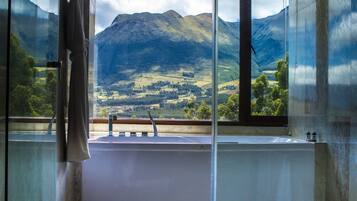 Ein Badezimmer mit einer Badewanne, einem Fenster mit Bergblick und einem Handtuch an der Tür.