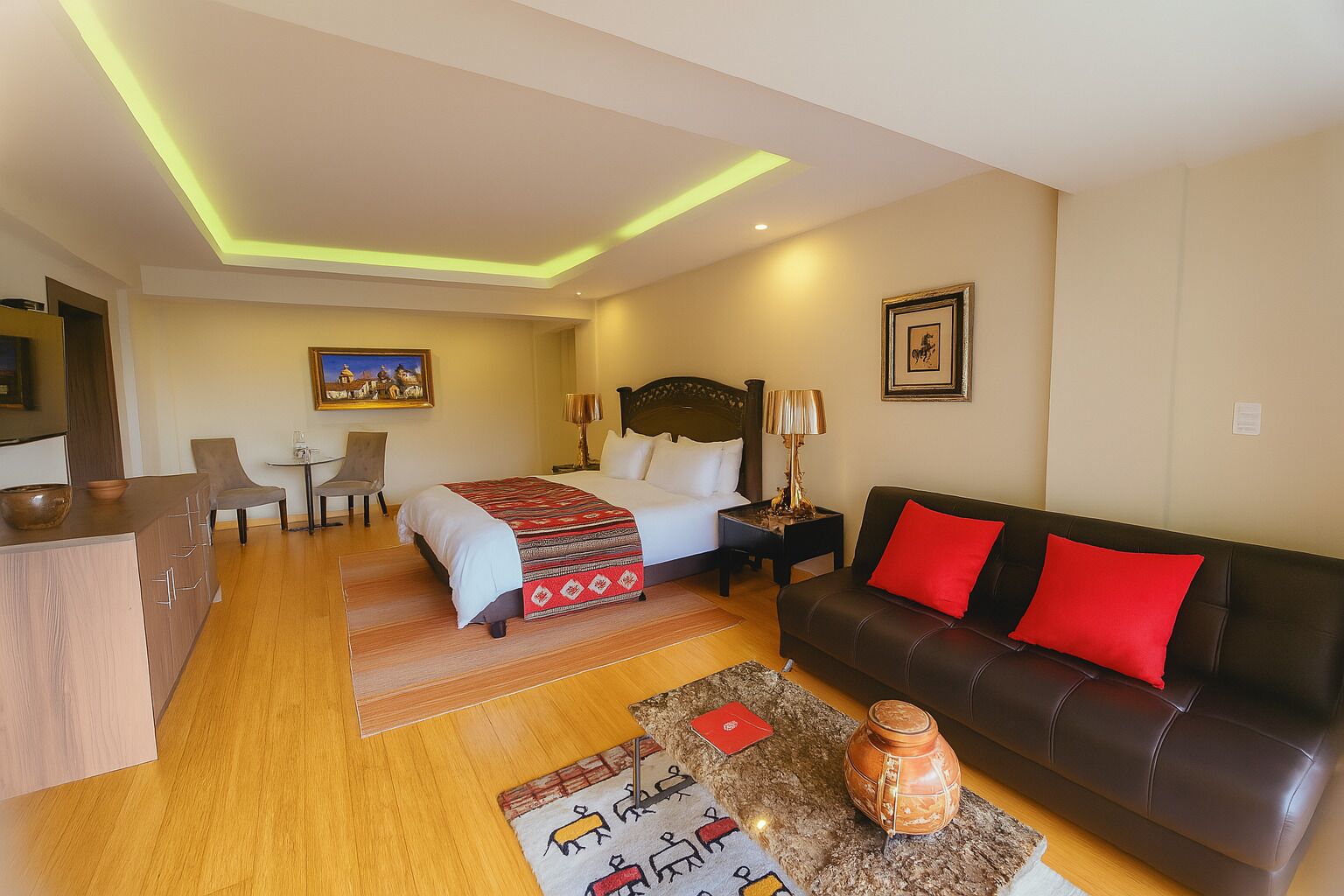A hotel room with a bed, a sofa, a desk, and a chair.