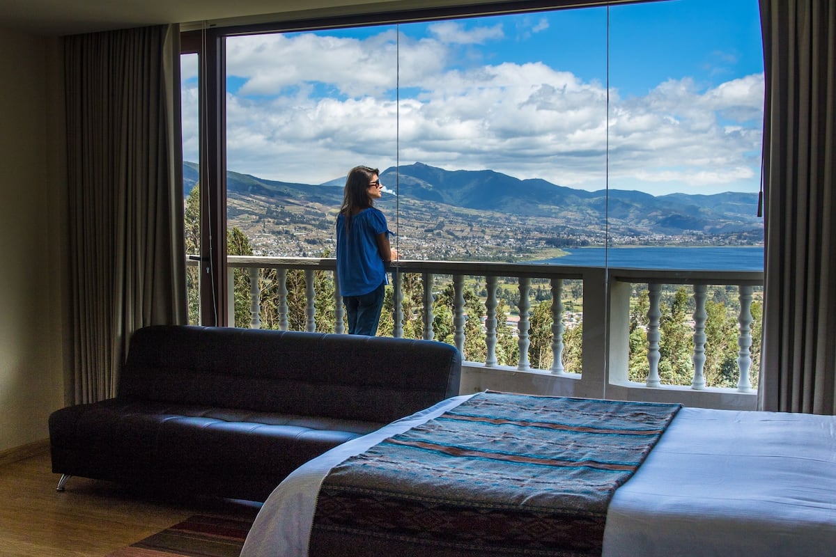 A room with a large window offering a view of mountains and a lake.